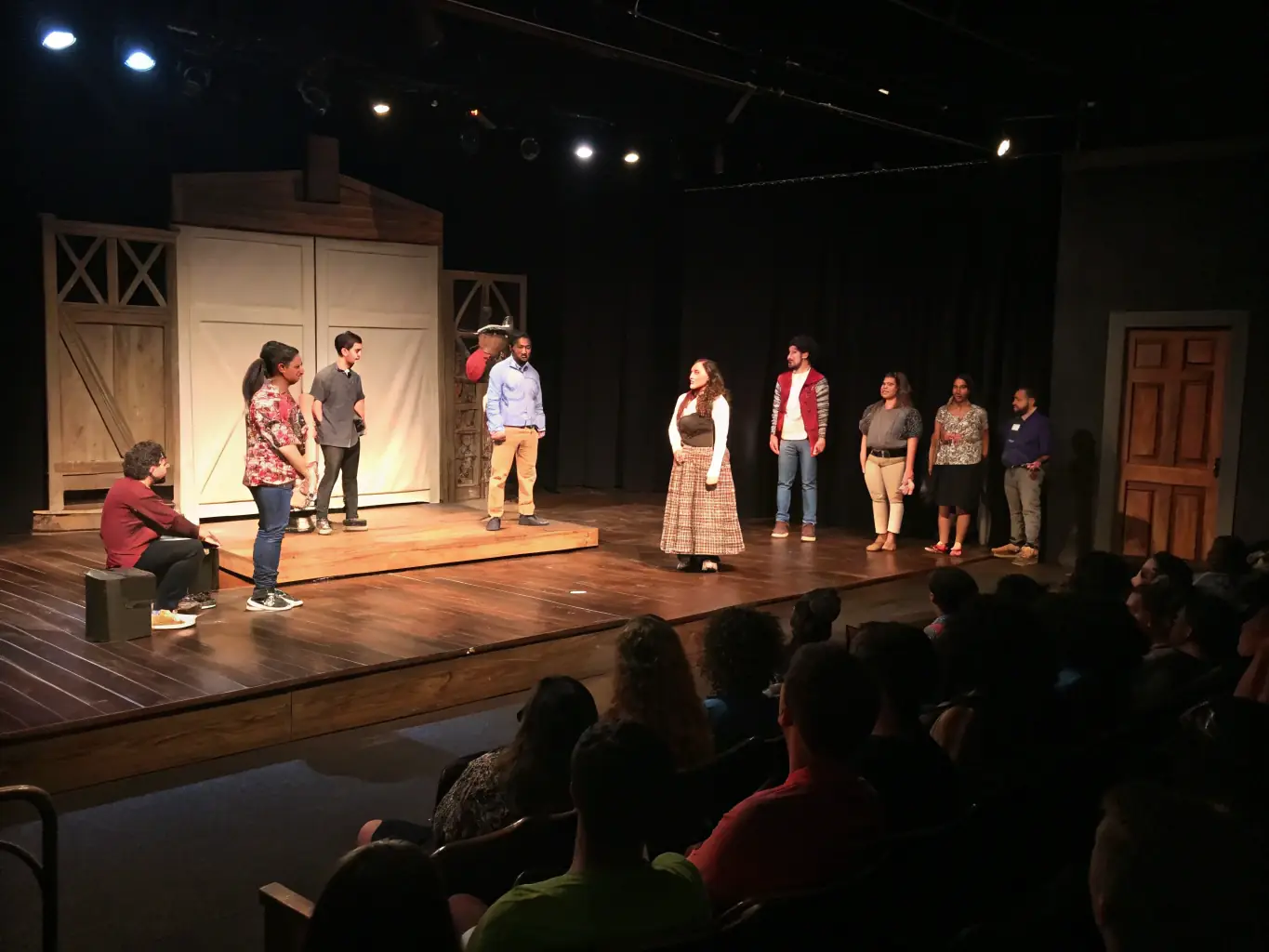 A community theater stage with local residents in costume rehearsing a play, set against a backdrop of simple props and enthusiastic audience members, reflecting the collaborative spirit of community theater.